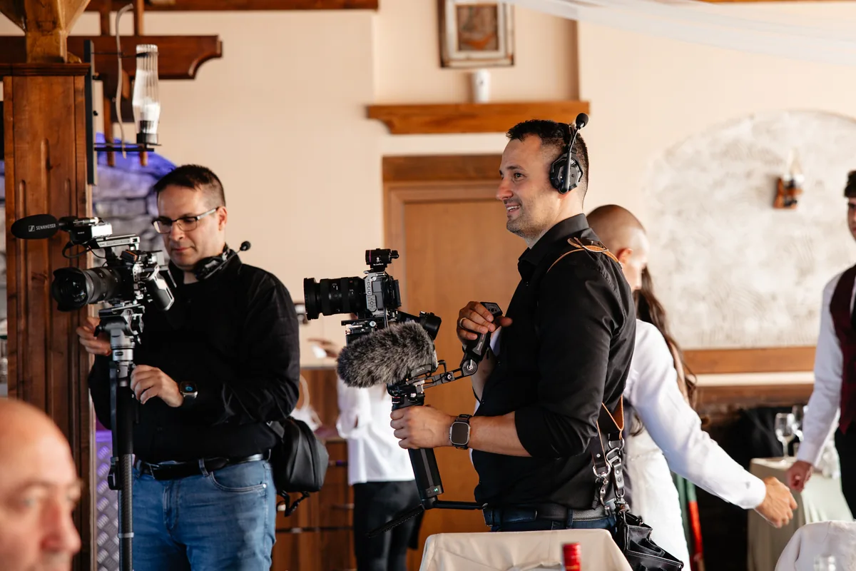 Two PhotoBros videographers filming a reception with camera rigs and microphones